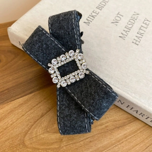 Barrette à cheveux élégante en tweed gris avec boucle strassée sur une surface en bois