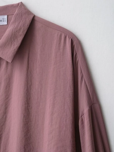 Detail of mauve soft shirt showing shoulder seam, neckline, and sizing label on fabric