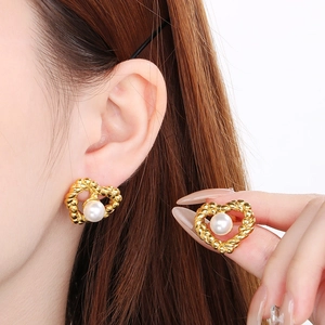 Detail of heart-shaped pearl earrings with golden twisted rope frame on a model
