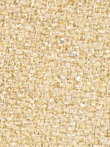 Macro view of metallic gold fabric with woven sequins and textured thread detail