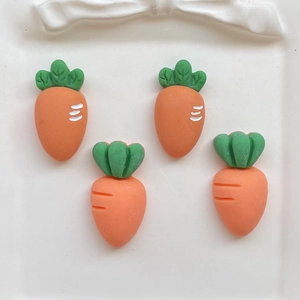 Close-up of four orange resin carrot charms for DIY crafts on a white decorative tray
