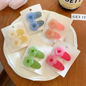 Detailed view of matte flower-shaped hair clips in blue, pink, white, green and rose colors