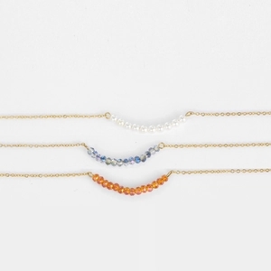 Layered gold beaded necklaces with white pearls and blue or orange crystals for women
