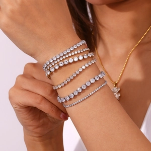 Close-up of stacked gold and silver tennis bracelets with cubic zirconia in various widths