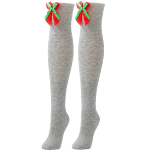 Close-up of gray over-knee socks with festive red and green satin bows for Christmas