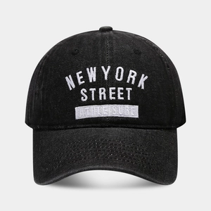 Detailed close-up of white NEW YORK STREET embroidery on black denim baseball cap fabric