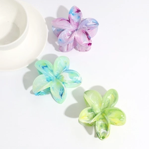 Detail shot of marble textured floral hair claws in gradient purple, teal and yellow colors