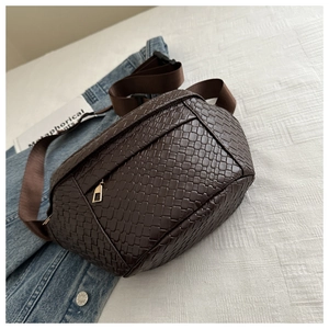 Detail showing deep brown woven leather texture with golden zipper on a stylish belt bag