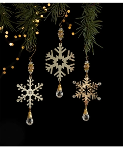 Detailed view of ornate metal snowflake ornaments with crystal drops on a pine tree