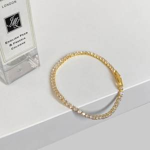 Detailed macro view of gold-plated tennis bracelet with shimmering cubic zirconia accents