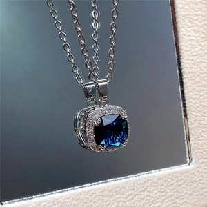 Macro shot of silver necklace with square blue gemstone pendant and sparkling accents