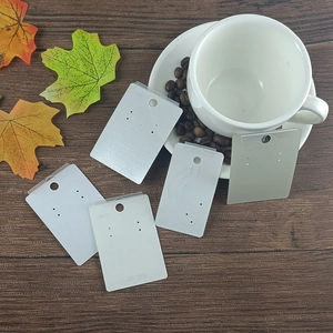 Detailed view of white vanilla paper earring display cards on a dark wood grain background