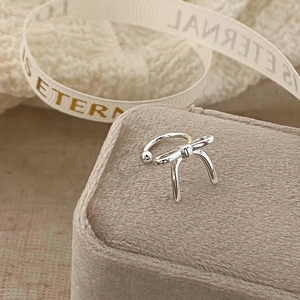 Macro shot of silver bow ear cuff with long streamers on a velvet jewelry box
