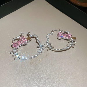 Macro detail of silver cat hoop earrings with sparkling white and pink crystals