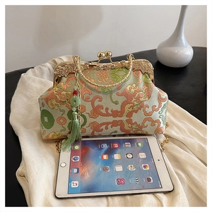 Detail of green embroidered kiss-lock bag with golden frame and elegant silk tassel