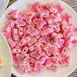 Close-up of pink pearlescent butterfly beads in a white ceramic dish for DIY jewelry
