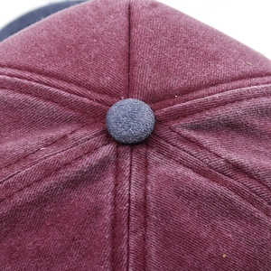 Detailed close-up of dark red washed cotton twill baseball cap crown and top button sewing