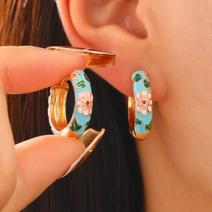 Detailed close-up of light blue enamel hoop earring with pink floral and gold patterns