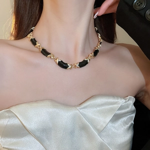 Détail du collier vintage en émail noir et or à maillons croisés sur le cou