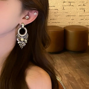 Details von silbernen Metall-Quastenohrringen mit Pailletten an einem Model