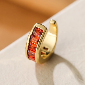 Close-up of gold-plated ear cuff with sparkling rectangular orange-red zircon stones