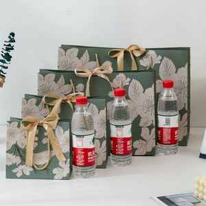 Dark green paper gift bags with floral patterns and golden ribbon bows in four sizes