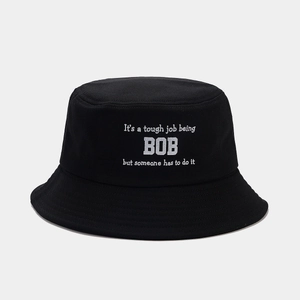 Gros plan du bob en coton noir montrant les coutures du bord et le texte imprimé en blanc