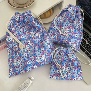 Three sizes of floral fabric drawstring storage bags on white table for travel