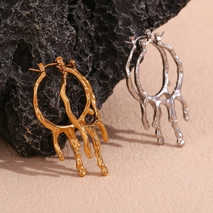 Detailaufnahme von Creolen mit Lava-Struktur in Gold- und Silberoptik auf Felsen