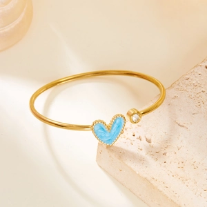Detailed shot of open gold bracelet featuring blue heart charm and sparkling zircon inlay