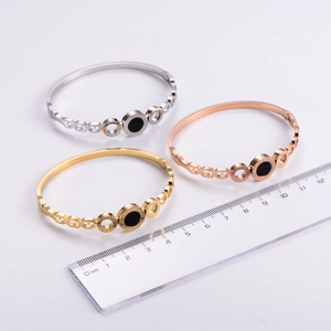 Flat lay view of rose gold, silver, and gold bangles featuring Roman numeral engravings