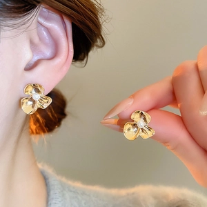 Detailed macro view of the golden flower earring with pearl center and hammered texture