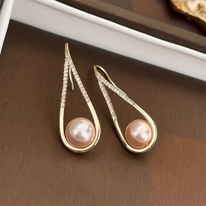Macro shot of gold hollow teardrop earrings with pink pearls and pave crystals