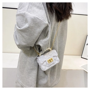 Detailed view of white quilted mini jelly bag with pearl handle and golden chain strap