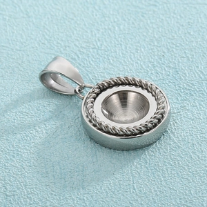 Close-up of a silver round pendant with textured rope edges and a large hanging bail