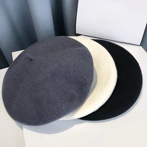 Flat lay of wool beret hats in dark grey, beige, and black colors for autumn and winter