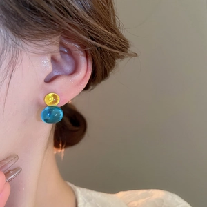 Close-up of elegant glass gourd earrings with yellow and blue beads on model ear