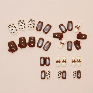 Detail of cat eye press-on nails featuring brown bows, leopard print, and cat designs