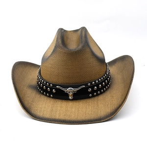 Detail of western straw hat featuring silver bull head emblem and studded leather band