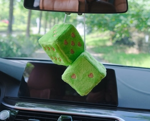 Close-up of green plush car dice hangers with brown heart-shaped dots on rearview mirror