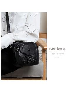 Détail du sac bandoulière en cuir souple noir avec rivets et boucles métalliques