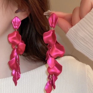 Macro detail of long rose red petal tassel earrings with a matte metallic texture