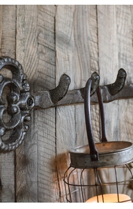 Detail of vintage cast iron key-shaped wall hook against light grey wooden backdrop