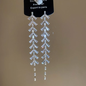 Vue détaillée des boucles d'oreilles feuilles en argent avec zircons sur carte noire