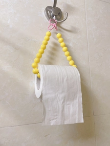 Detail of yellow beaded toilet paper holder with heart clip in bathroom setting