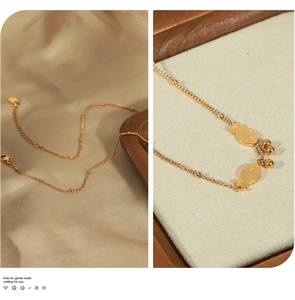 Macro detail of golden twin fish pendants and bead chain on elegant satin and tray