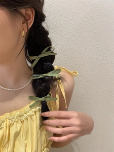 Drie groene satijnen strik haarspelden in een vlecht voor een stijlvolle zomerse look