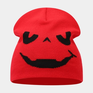 Close-up of red knitted beanie featuring black spooky pumpkin smile jacquard pattern