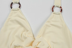 Detail of beige knit dress featuring deep V-neckline and vintage tortoiseshell rings