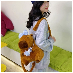 Close-up of plush Capybara backpack with a blue bow and small rabbit doll accessory
